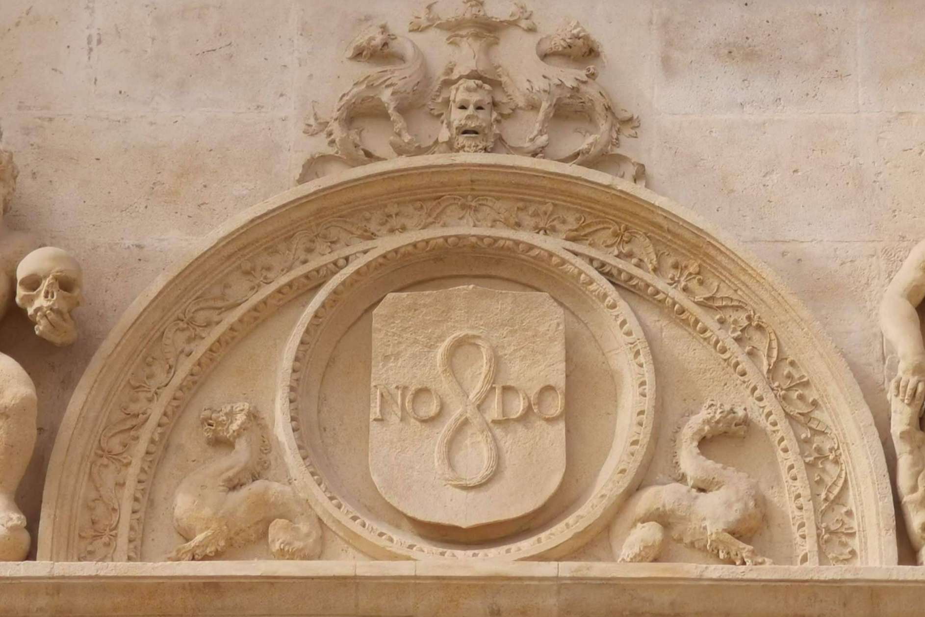 ¿Qué simboliza la inscripción ubicada en diferentes lugares de Sevilla, NO8DO?